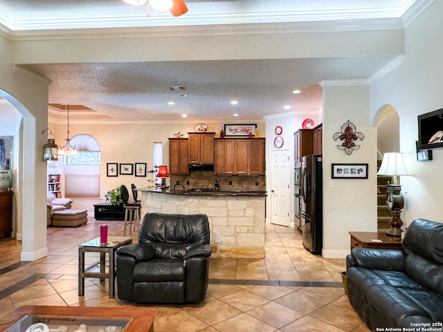 tiled living room with a textured ceiling, a chandelier, and ornamental molding