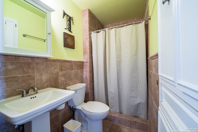 bathroom with toilet, tile patterned floors, backsplash, tile walls, and sink