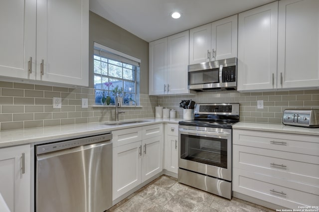 kitchen featuring light tile patterned flooring, appliances with stainless steel finishes, sink, and white cabinetry