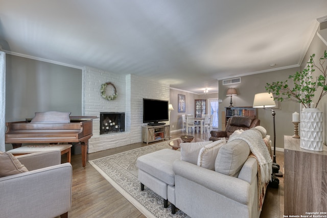 living room featuring light hardwood / wood-style flooring, crown molding, brick wall, and a brick fireplace