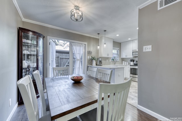 dining space with sink, crown molding, and light hardwood / wood-style floors