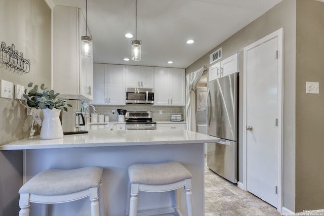 kitchen with decorative backsplash, stainless steel appliances, kitchen peninsula, and white cabinetry