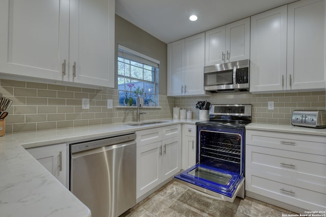 kitchen with white cabinetry, appliances with stainless steel finishes, light tile patterned floors, backsplash, and sink