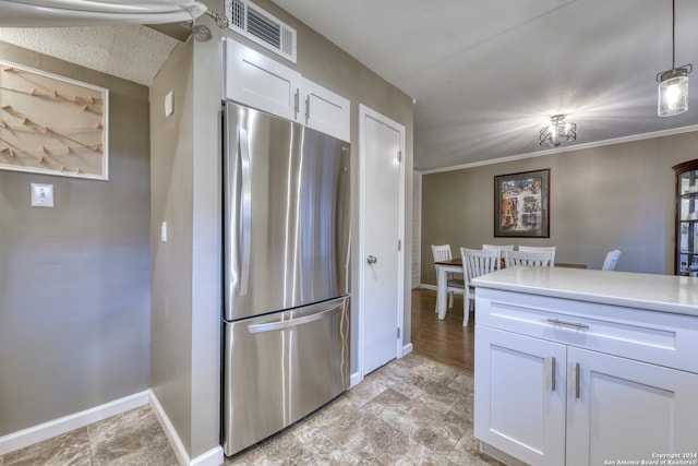 kitchen with light tile patterned floors, white cabinets, decorative light fixtures, and stainless steel fridge