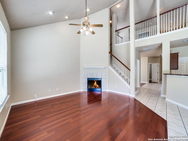 unfurnished room featuring high vaulted ceiling, ceiling fan with notable chandelier, and light wood-type flooring