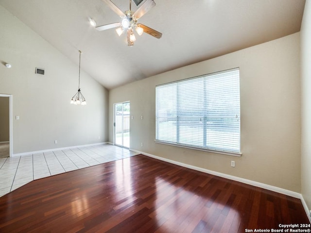 empty room featuring light tile patterned flooring, high vaulted ceiling, and ceiling fan with notable chandelier