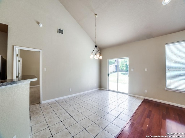 unfurnished room with an inviting chandelier, high vaulted ceiling, and light tile patterned floors