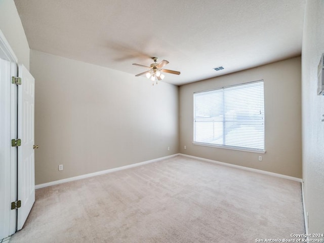 carpeted spare room with ceiling fan and plenty of natural light