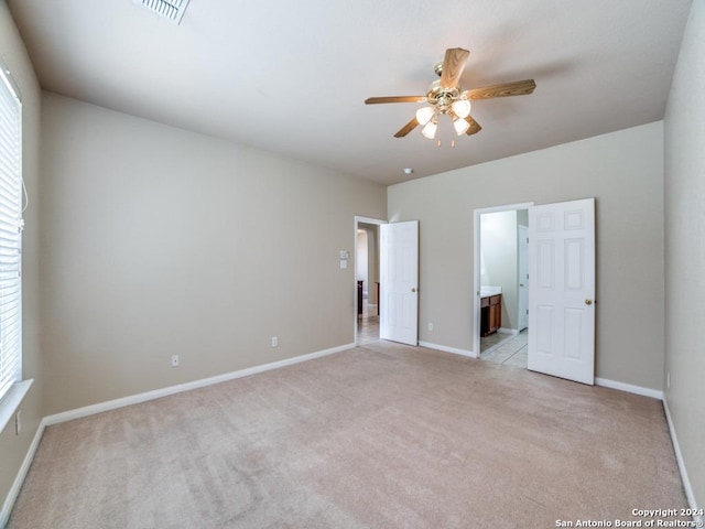 unfurnished bedroom featuring ceiling fan, ensuite bath, and light carpet