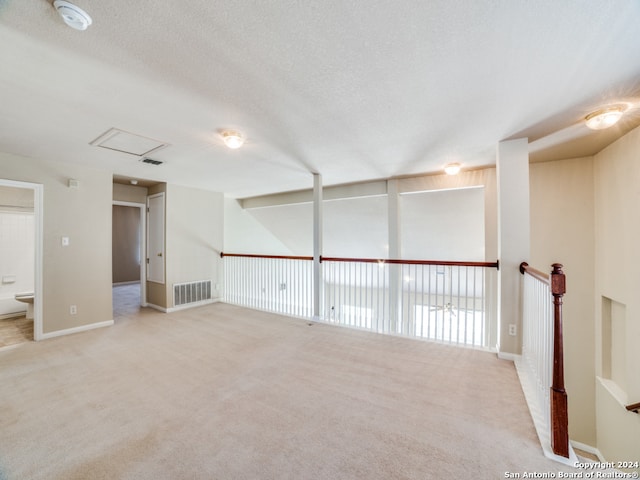 carpeted empty room featuring a textured ceiling