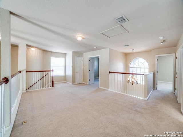 unfurnished room with light colored carpet and a chandelier