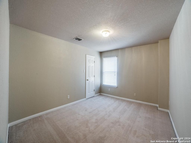 unfurnished room with light carpet and a textured ceiling