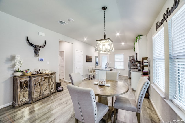 dining space featuring light hardwood / wood-style floors, sink, and an inviting chandelier