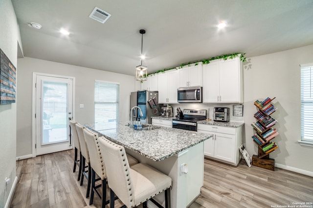 kitchen featuring appliances with stainless steel finishes, sink, light hardwood / wood-style flooring, and an island with sink