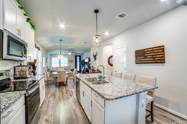 kitchen with sink, light hardwood / wood-style flooring, appliances with stainless steel finishes, and an island with sink