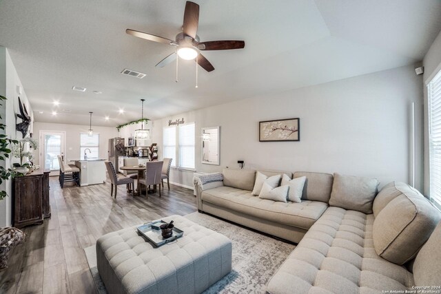 living room with ceiling fan, light hardwood / wood-style floors, and sink