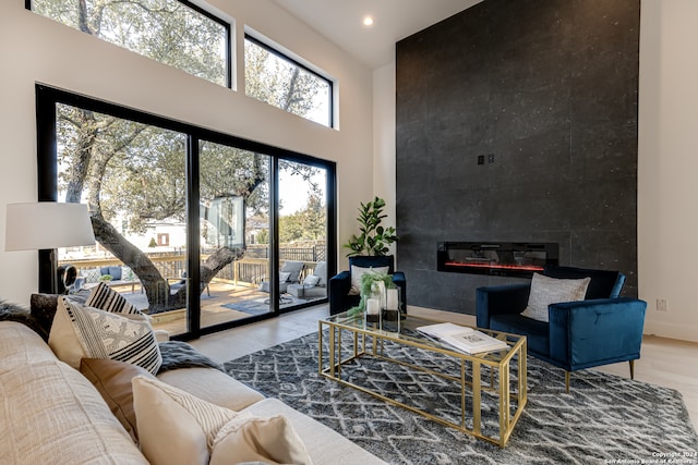 living room with light hardwood / wood-style flooring, a fireplace, and a towering ceiling