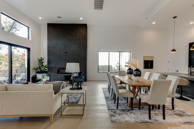 dining area featuring a towering ceiling, plenty of natural light, and light hardwood / wood-style floors