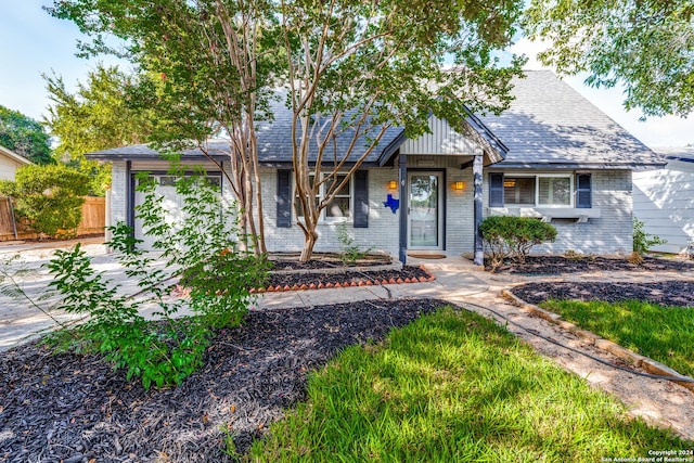 view of front of property with roof with shingles, fence, and brick siding