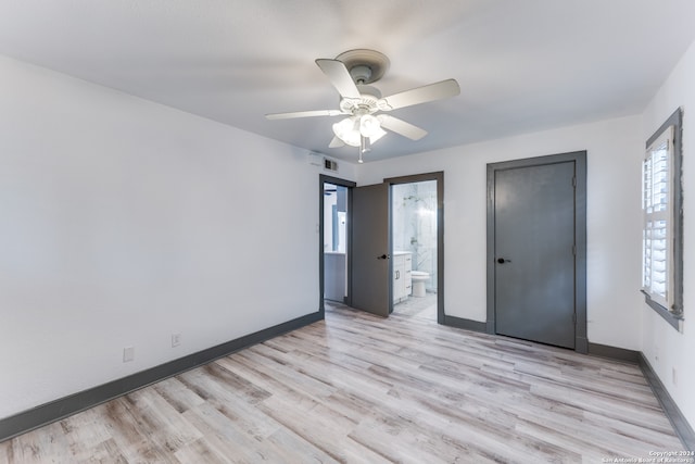 unfurnished bedroom featuring ceiling fan, light hardwood / wood-style flooring, ensuite bathroom, and multiple windows