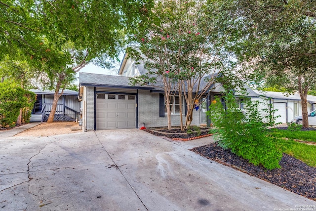 ranch-style home featuring concrete driveway, brick siding, an attached garage, and a shingled roof