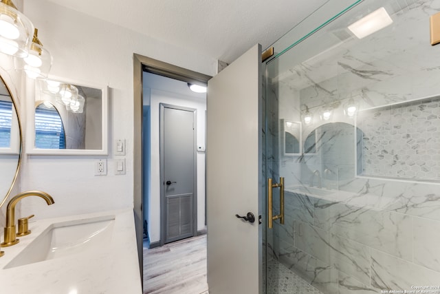 bathroom featuring a shower with shower door, hardwood / wood-style flooring, vanity, and a textured ceiling