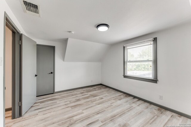 additional living space with light wood-type flooring and vaulted ceiling