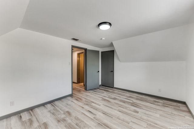 additional living space with light wood-type flooring and lofted ceiling