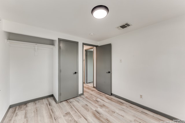 unfurnished bedroom with light wood-type flooring and a closet