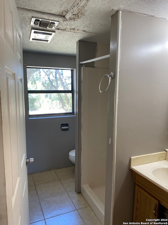 bathroom with vanity, tile patterned floors, a textured ceiling, toilet, and walk in shower