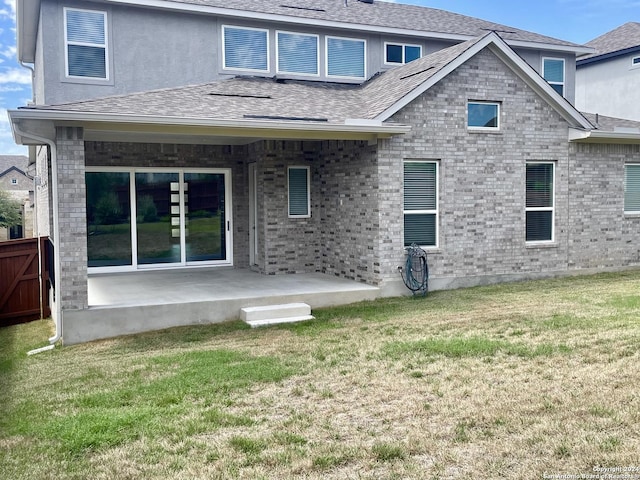 rear view of house with a lawn, fence, and a shingled roof