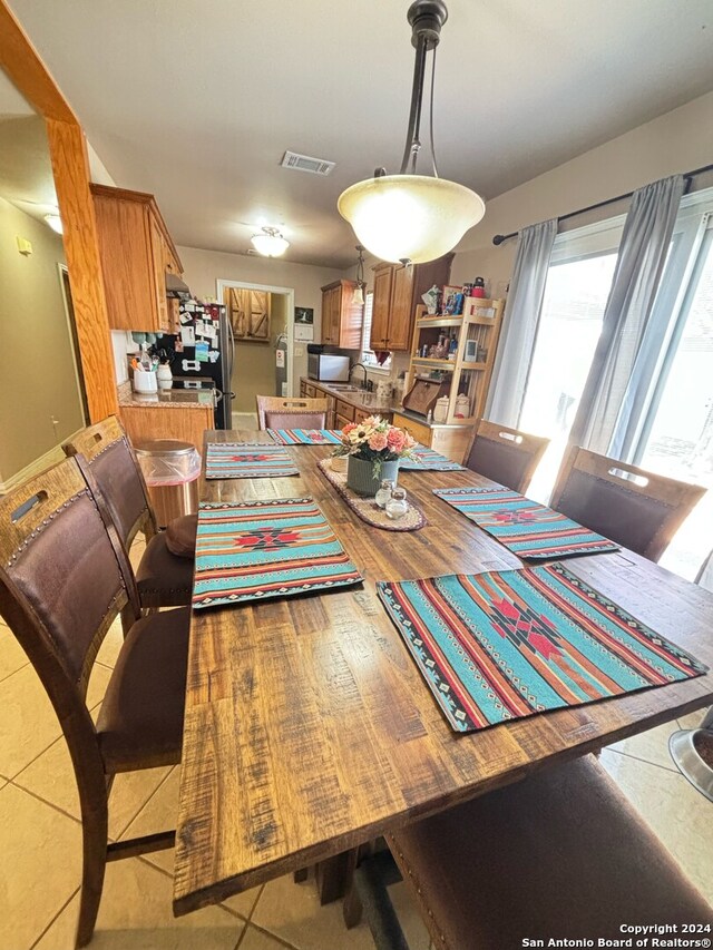 kitchen with stainless steel refrigerator, light tile patterned floors, washing machine and dryer, sink, and hanging light fixtures