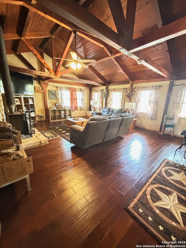 interior space with beamed ceiling, a wood stove, ceiling fan, wooden ceiling, and hardwood / wood-style flooring