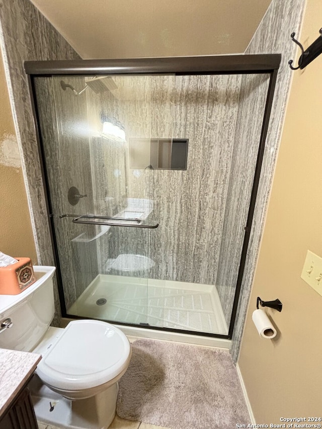 bathroom featuring an enclosed shower, toilet, and vanity