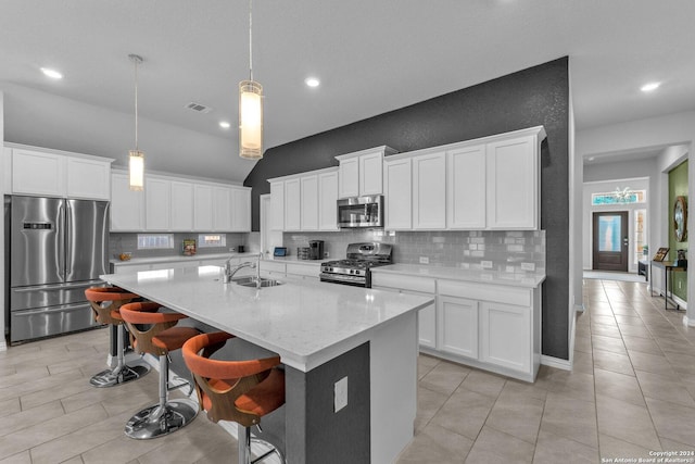 kitchen featuring white cabinets, stainless steel appliances, a center island with sink, and pendant lighting