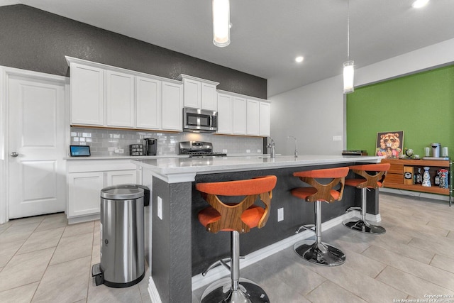 kitchen with white cabinets, light countertops, appliances with stainless steel finishes, decorative backsplash, and decorative light fixtures