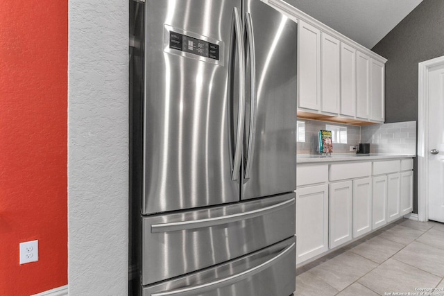 kitchen with tasteful backsplash, freestanding refrigerator, light countertops, and white cabinetry