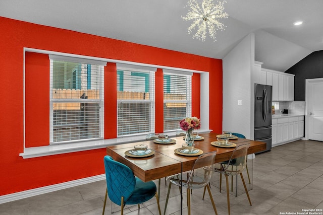 tiled dining area featuring lofted ceiling, baseboards, and a chandelier