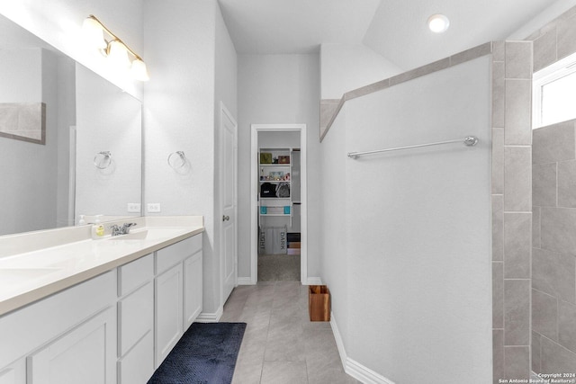 bathroom featuring double vanity, tile patterned flooring, a sink, and baseboards