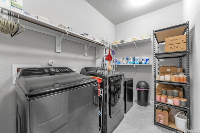 clothes washing area featuring washing machine and dryer, laundry area, and light tile patterned flooring