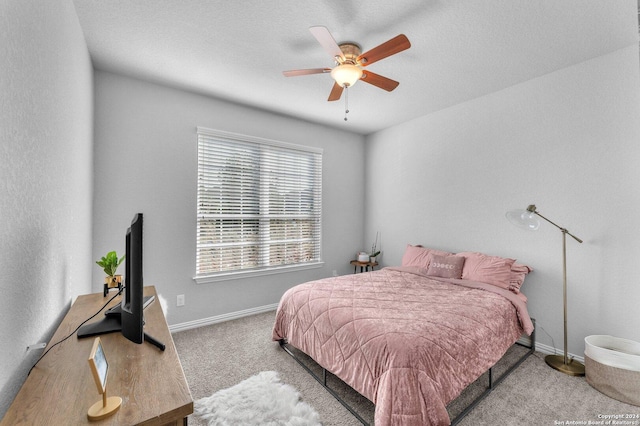 bedroom with ceiling fan, baseboards, a textured ceiling, and light colored carpet