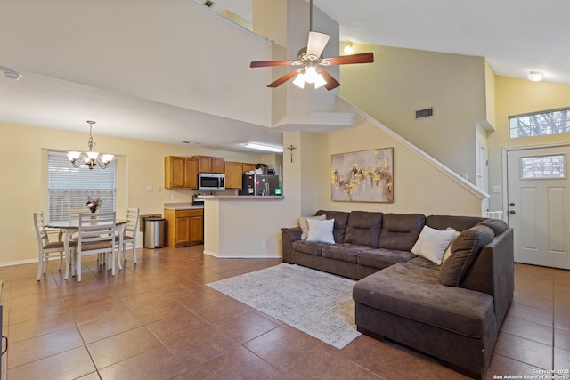 living room with high vaulted ceiling, ceiling fan with notable chandelier, and tile patterned floors