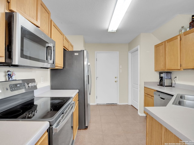 kitchen featuring appliances with stainless steel finishes, sink, light tile patterned floors, light brown cabinets, and a textured ceiling