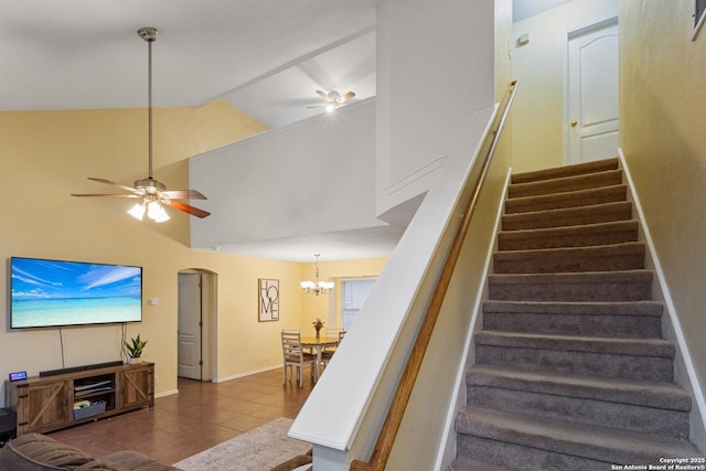 staircase with tile patterned flooring, ceiling fan with notable chandelier, and high vaulted ceiling