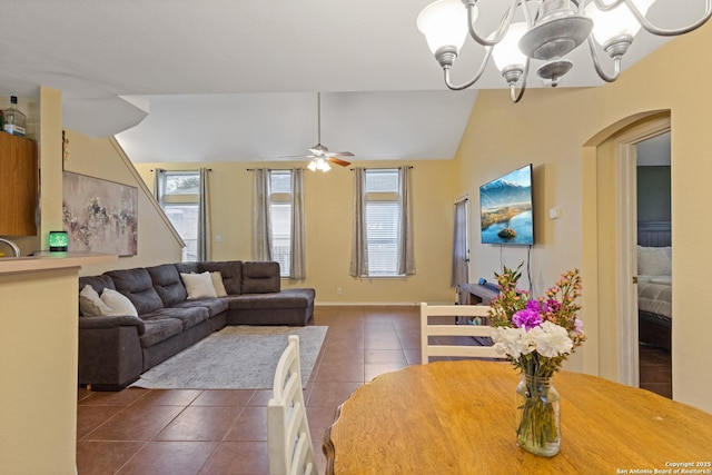 tiled living room with vaulted ceiling, ceiling fan with notable chandelier, and a wealth of natural light