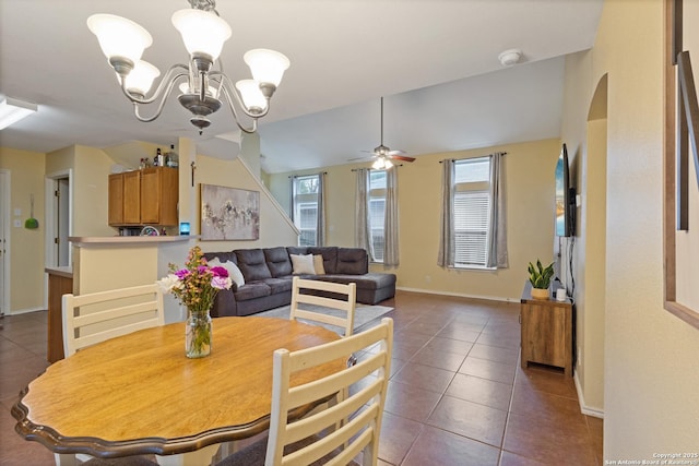 tiled dining space with ceiling fan with notable chandelier, a healthy amount of sunlight, and vaulted ceiling