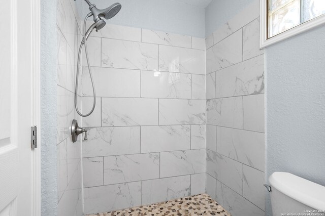 bathroom featuring a tile shower and toilet