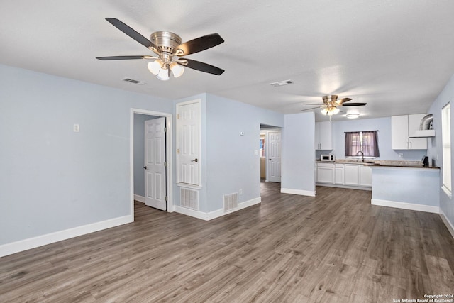 unfurnished living room featuring ceiling fan, sink, and hardwood / wood-style flooring