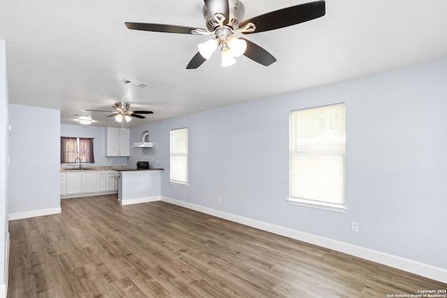 unfurnished living room featuring ceiling fan, sink, and light hardwood / wood-style floors