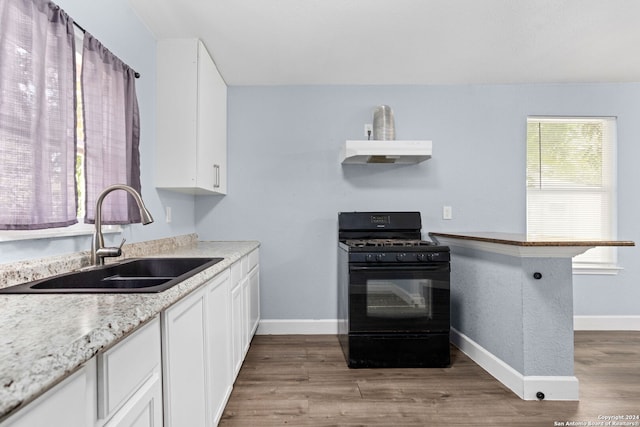 kitchen with kitchen peninsula, white cabinets, black gas range oven, light wood-type flooring, and sink